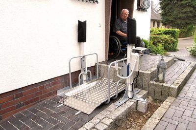 Afbeelding van een platformlift buiten en man in rolstoel