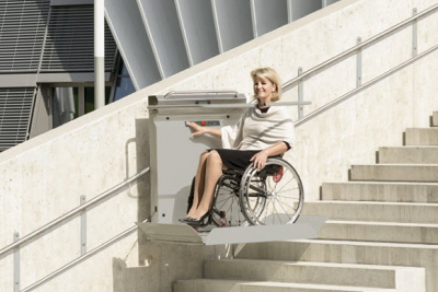 Vrouw in rolstoel in een rolstoellift op een trap