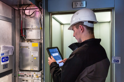 Afbeelding van een liftmonteur in de lift met een witte helm op