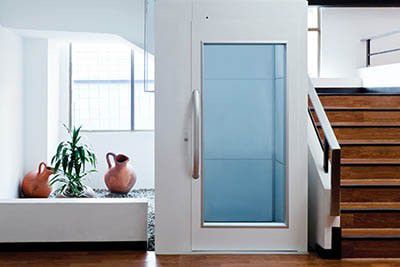 Witte lift met glazen raam naast een trap